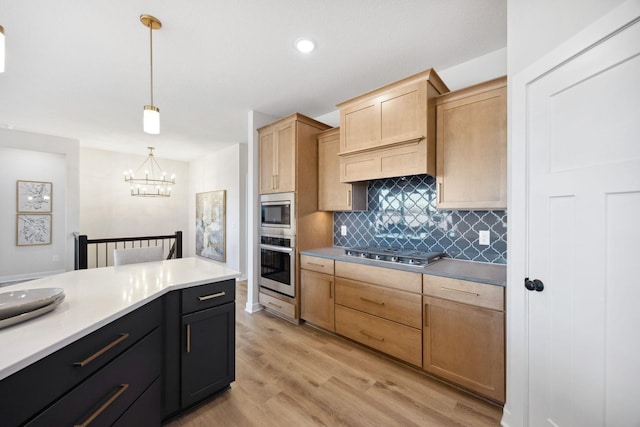 kitchen featuring backsplash, a notable chandelier, pendant lighting, light wood-type flooring, and appliances with stainless steel finishes