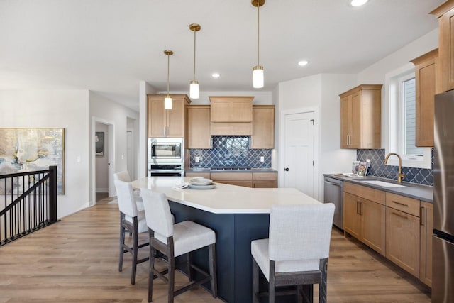 kitchen with backsplash, a kitchen island, sink, hanging light fixtures, and stainless steel appliances