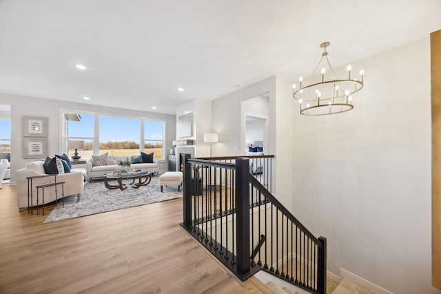 interior space with an upstairs landing, recessed lighting, baseboards, a chandelier, and wood finished floors