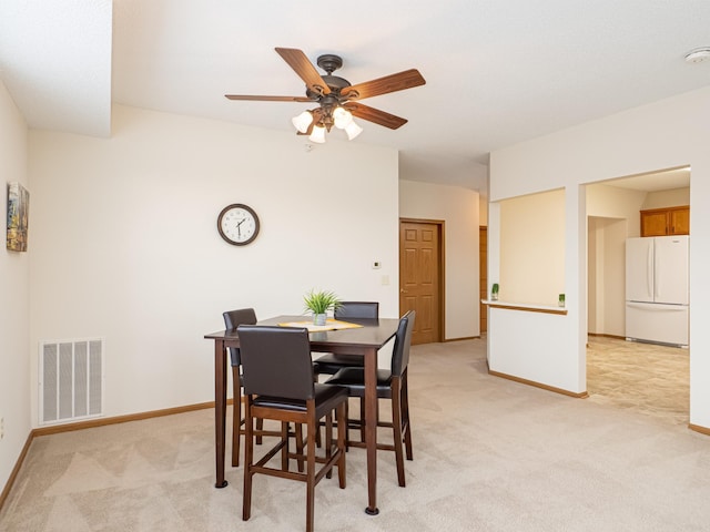 carpeted dining space with ceiling fan