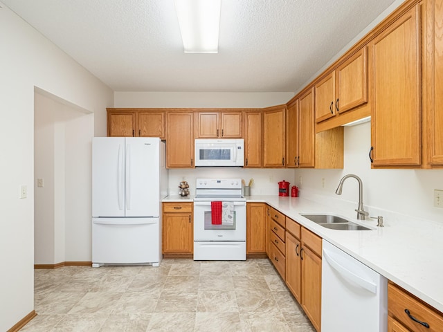 kitchen with a textured ceiling, white appliances, and sink