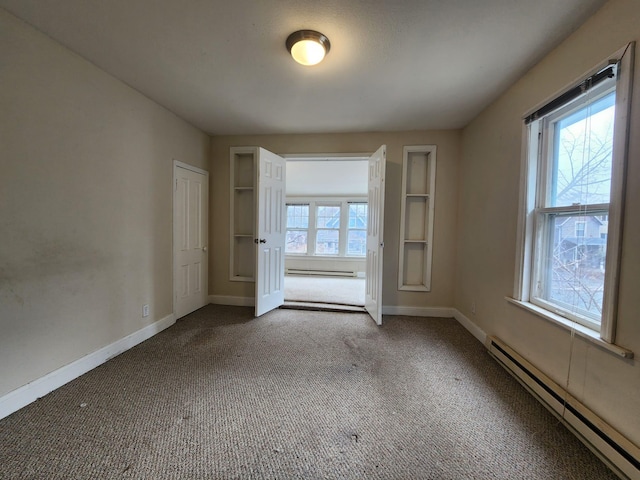 carpeted empty room featuring baseboard heating