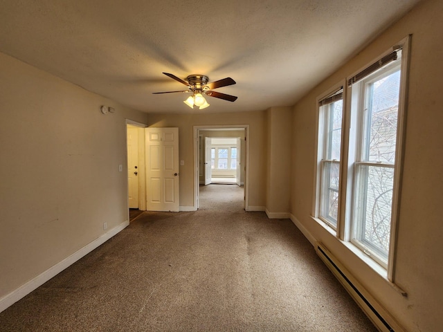 carpeted empty room featuring ceiling fan and a baseboard heating unit