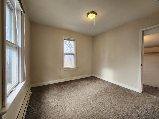 unfurnished bedroom with baseboard heating, a closet, and dark carpet