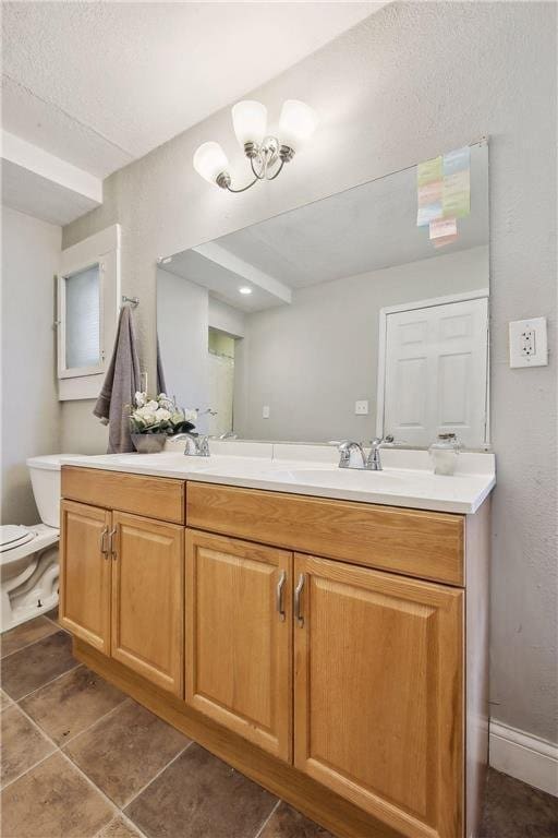 bathroom with tile patterned flooring, vanity, toilet, and a chandelier