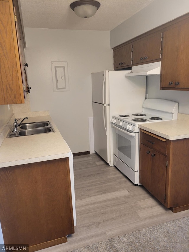 kitchen featuring a textured ceiling, sink, white appliances, and light wood-type flooring