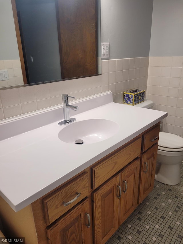 bathroom with tile patterned floors, vanity, tile walls, and toilet