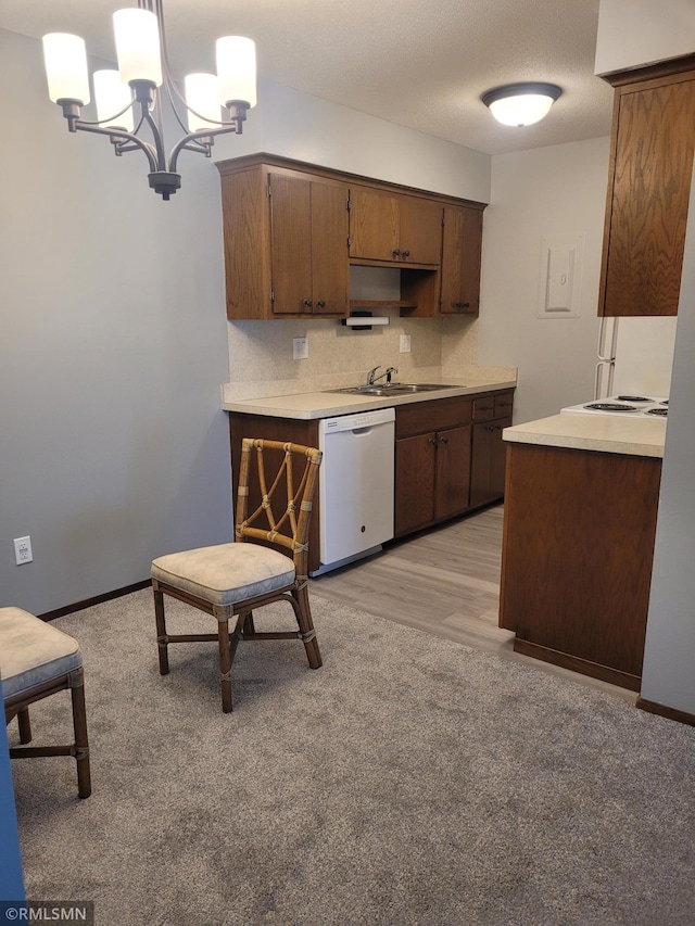 kitchen with white dishwasher, sink, pendant lighting, a notable chandelier, and light hardwood / wood-style floors