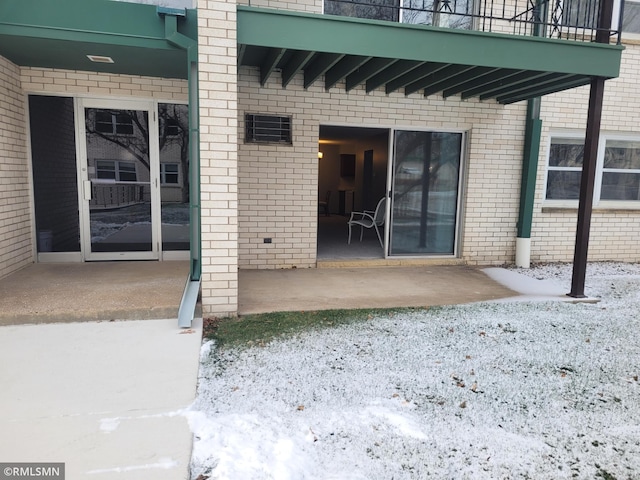 snow covered property entrance featuring a patio area and a balcony