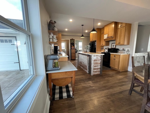 kitchen featuring dark hardwood / wood-style floors, decorative light fixtures, a breakfast bar area, a center island with sink, and black appliances