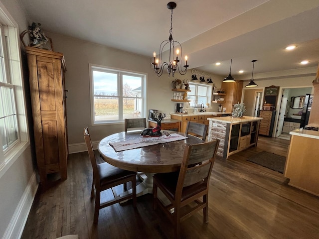 dining space with sink, dark hardwood / wood-style flooring, and an inviting chandelier