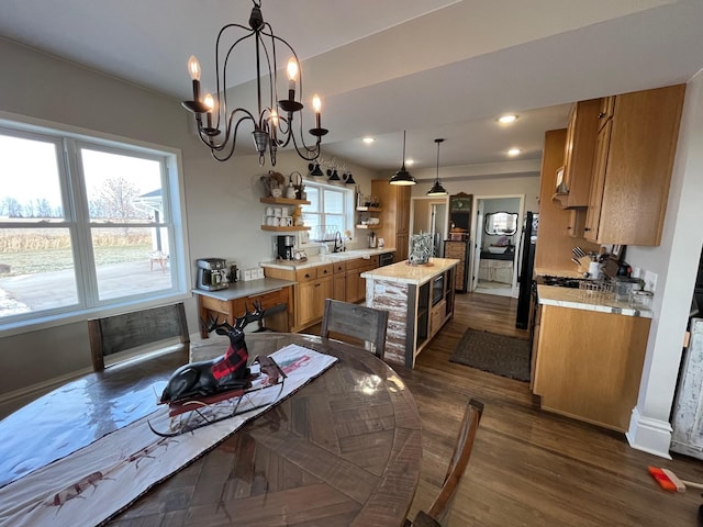 kitchen with a center island, sink, dark wood-type flooring, hanging light fixtures, and a chandelier