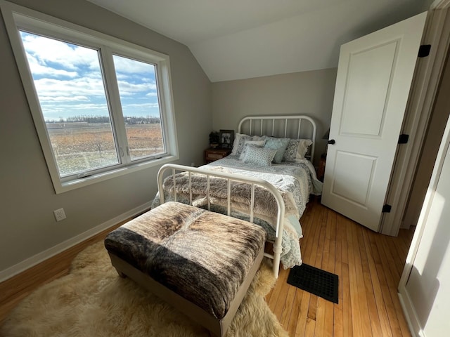 bedroom featuring light wood-type flooring, multiple windows, and lofted ceiling