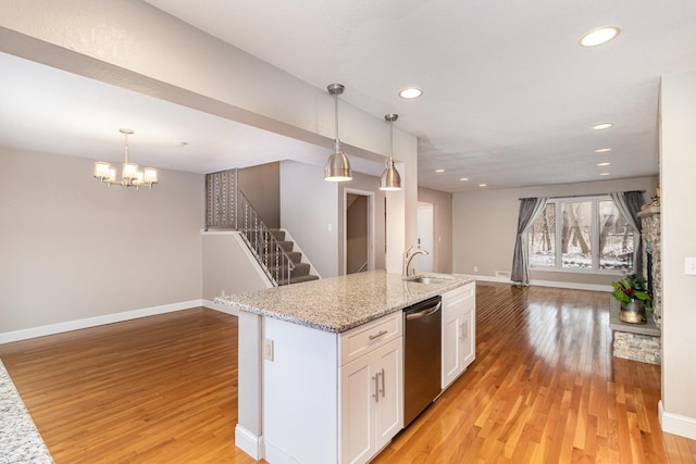 kitchen featuring light wood-type flooring, white cabinets, sink, dishwasher, and hanging light fixtures