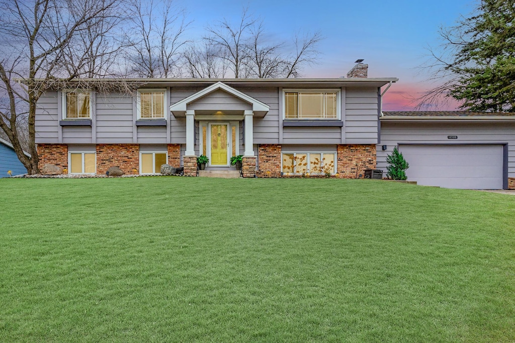 bi-level home featuring a yard and a garage