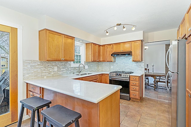 kitchen with a breakfast bar, backsplash, sink, appliances with stainless steel finishes, and kitchen peninsula