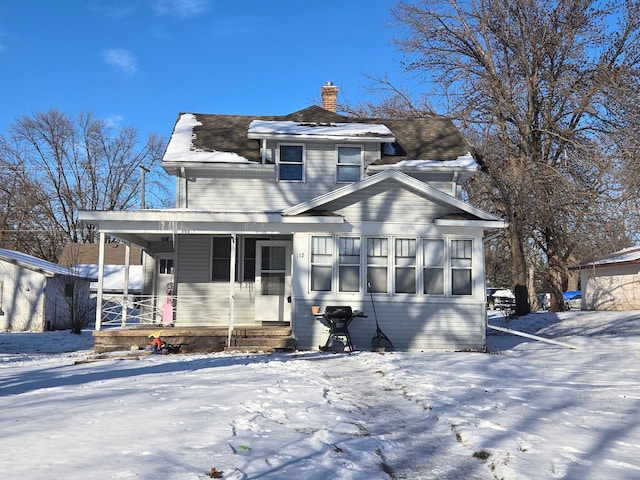 snow covered back of property featuring a porch