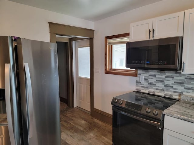 kitchen featuring light stone countertops, white cabinetry, stainless steel appliances, backsplash, and hardwood / wood-style floors