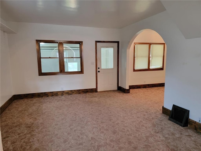 carpeted empty room featuring vaulted ceiling