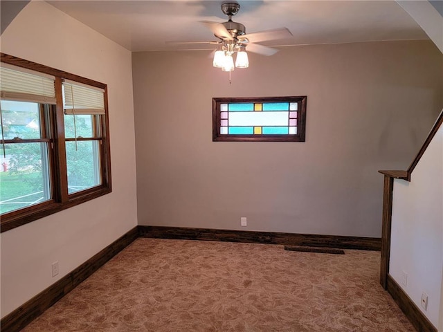 spare room with dark colored carpet, ceiling fan, and a healthy amount of sunlight