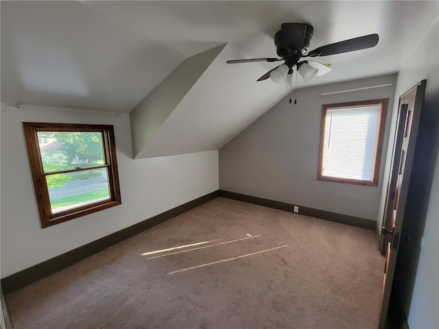 additional living space with carpet flooring, vaulted ceiling, a wealth of natural light, and ceiling fan