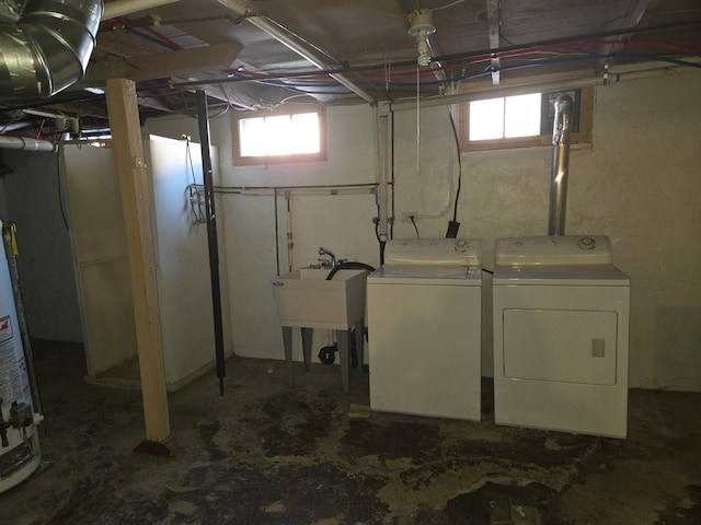 basement featuring washing machine and dryer, sink, and gas water heater