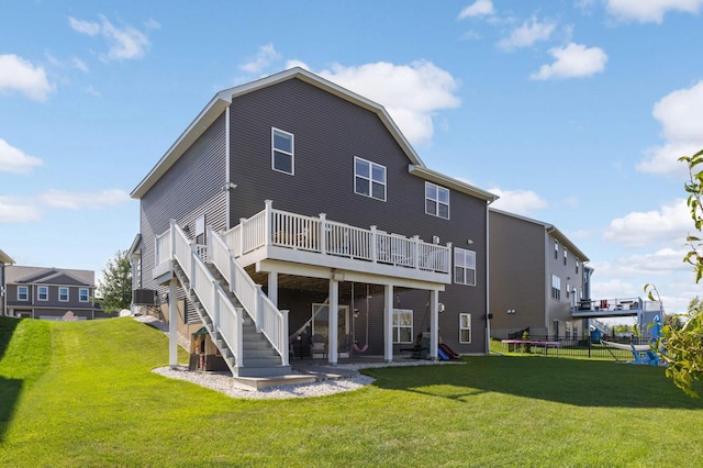 rear view of house with a yard, a deck, and a trampoline