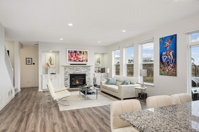 living room featuring wood-type flooring and a stone fireplace