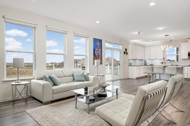 living room featuring dark hardwood / wood-style flooring, a notable chandelier, and plenty of natural light