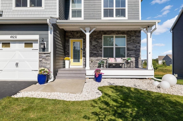 entrance to property with a garage, covered porch, and a lawn