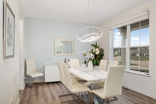 dining room with dark hardwood / wood-style floors and an inviting chandelier