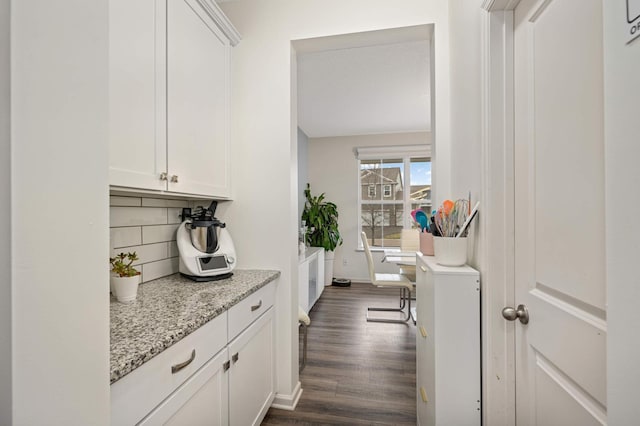 bar featuring backsplash, dark wood-type flooring, light stone countertops, and white cabinets