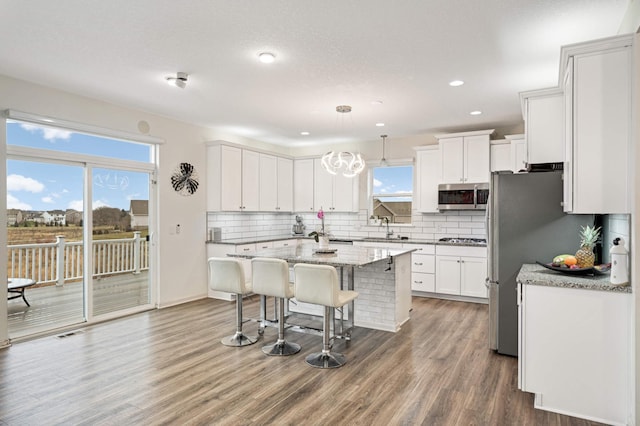 kitchen with a breakfast bar, white cabinetry, hanging light fixtures, a kitchen island, and stainless steel appliances