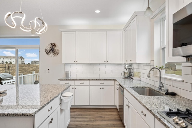 kitchen featuring stainless steel appliances, sink, white cabinets, and decorative light fixtures