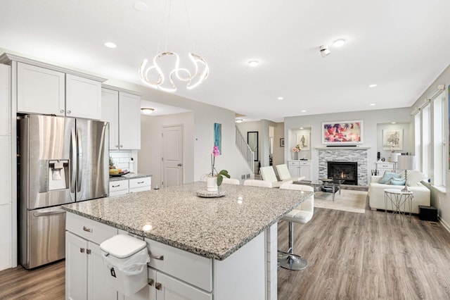 kitchen featuring pendant lighting, stainless steel fridge, white cabinetry, a kitchen breakfast bar, and a kitchen island