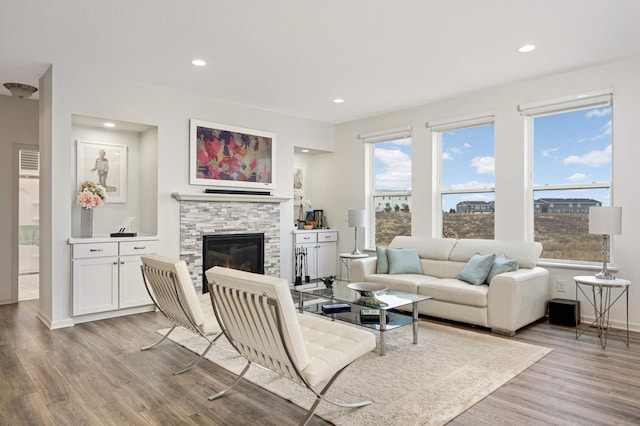 living room with a stone fireplace and light hardwood / wood-style floors