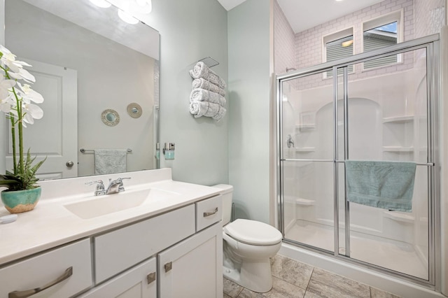 bathroom with a shower with door, vanity, and toilet