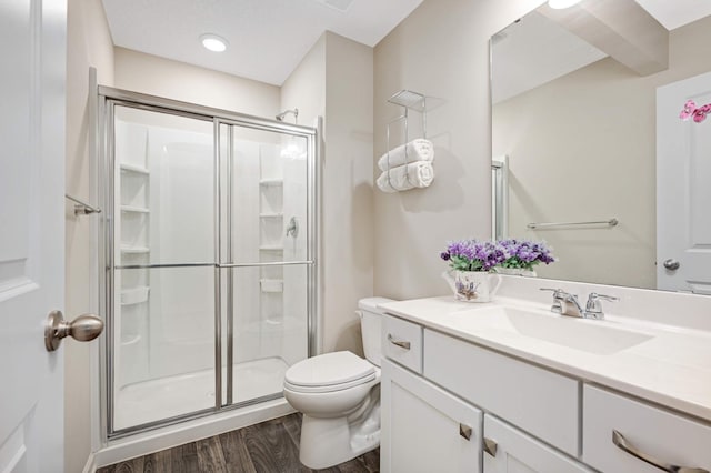 bathroom with hardwood / wood-style flooring, vanity, toilet, and an enclosed shower