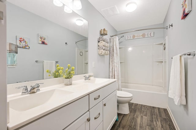 full bathroom featuring shower / tub combo with curtain, hardwood / wood-style floors, vanity, a textured ceiling, and toilet