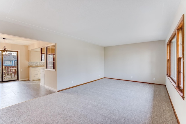 spare room with light colored carpet and an inviting chandelier