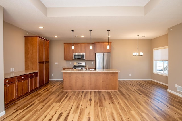 kitchen with pendant lighting, a notable chandelier, light wood-type flooring, and stainless steel appliances