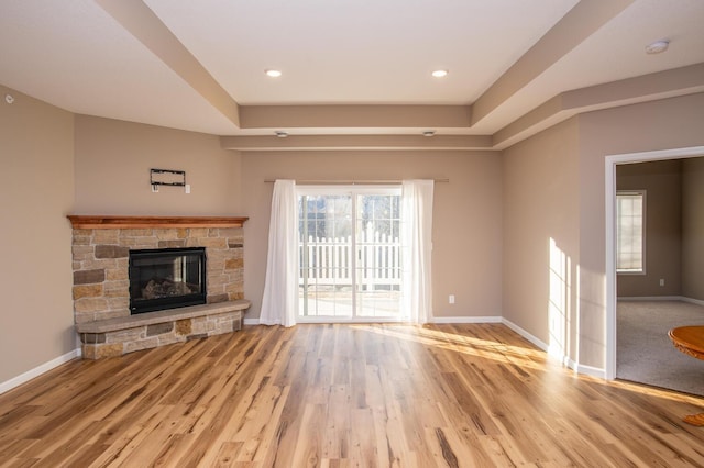 unfurnished living room with light hardwood / wood-style flooring and a stone fireplace