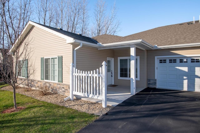 view of property exterior with an attached garage, fence, stone siding, and roof with shingles