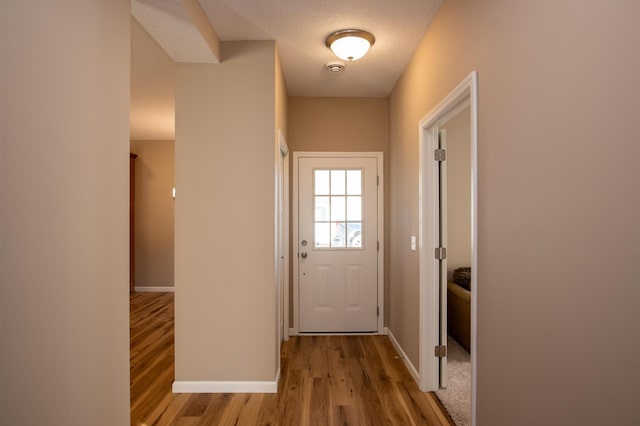 entryway featuring baseboards, a textured ceiling, and wood finished floors