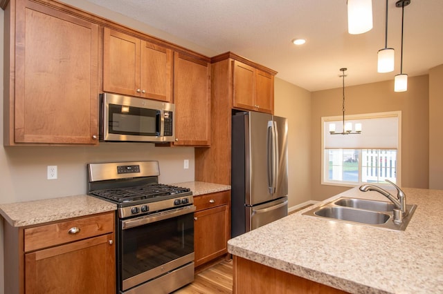 kitchen with brown cabinets, a sink, decorative light fixtures, stainless steel appliances, and light countertops