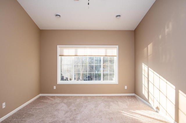 spare room featuring baseboards, light carpet, and visible vents