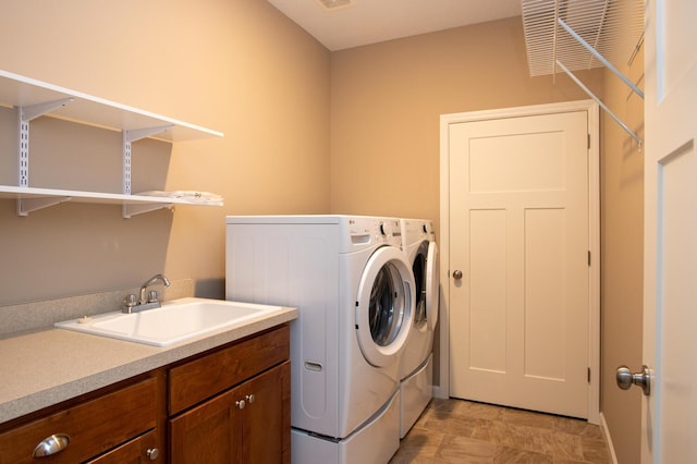 washroom with laundry area, separate washer and dryer, visible vents, and a sink