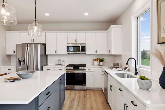 kitchen with white cabinets, decorative light fixtures, sink, and appliances with stainless steel finishes