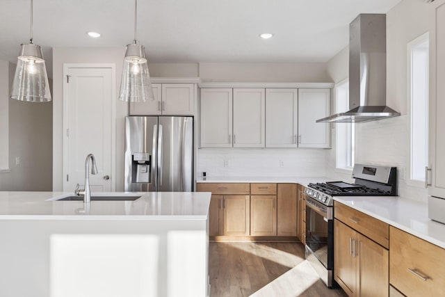 kitchen with pendant lighting, white cabinetry, sink, stainless steel appliances, and wall chimney range hood