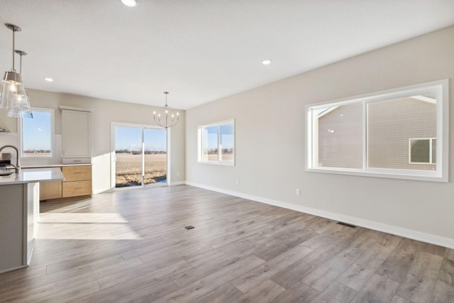 unfurnished dining area with an inviting chandelier and light hardwood / wood-style floors